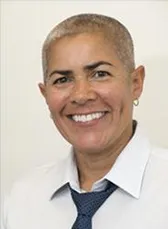 A woman wearing a white dress shirt and blue ties smiles into the camera